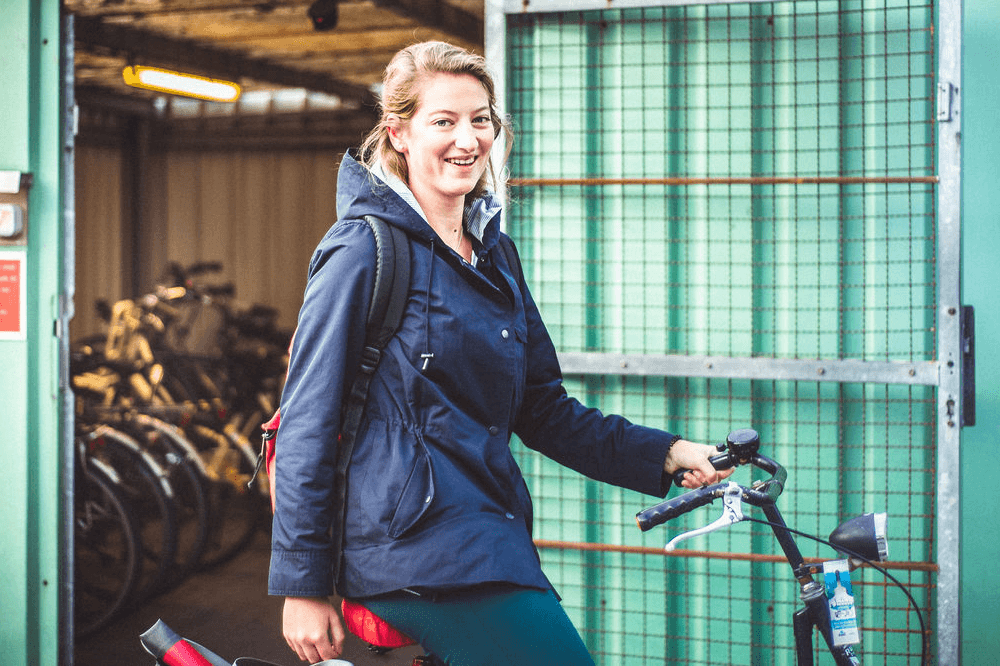Vrouw poseert met fiets voor bewaakte fietsenstalling