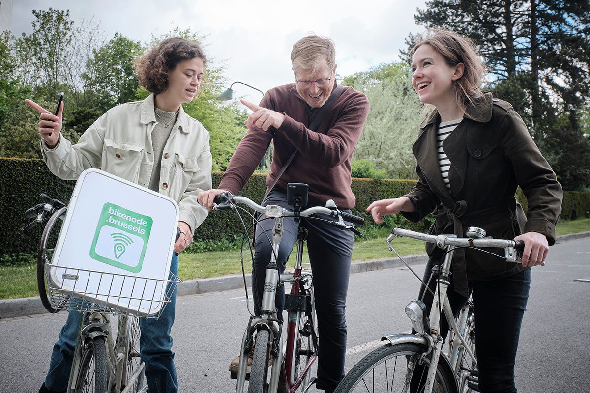 Groepje van drie fietsers gebruiken Bikenode, een app om een route door Brussel te plannen.