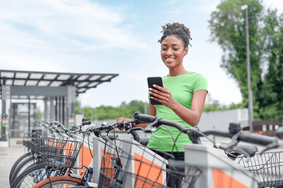 Vrouw neemt haar fiets en kijkt op haar smartphone