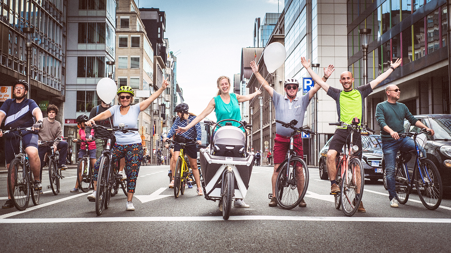 Groep van fietsers staat midden op straat en steken de handen in de lucht
