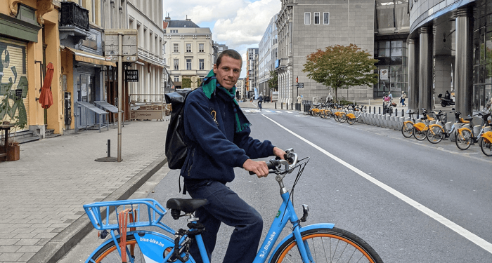 Julian Devos staat naast een blue-bike in Brussel