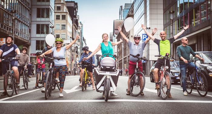 Groep van fietsers staat midden op straat en steken de handen in de lucht